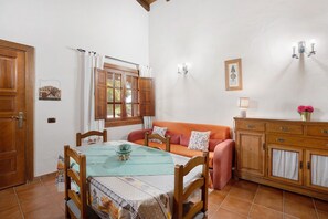 Une pièce comprenant une table à manger, des chaises, un canapé, un meuble et une fenêtre avec des rideaux.