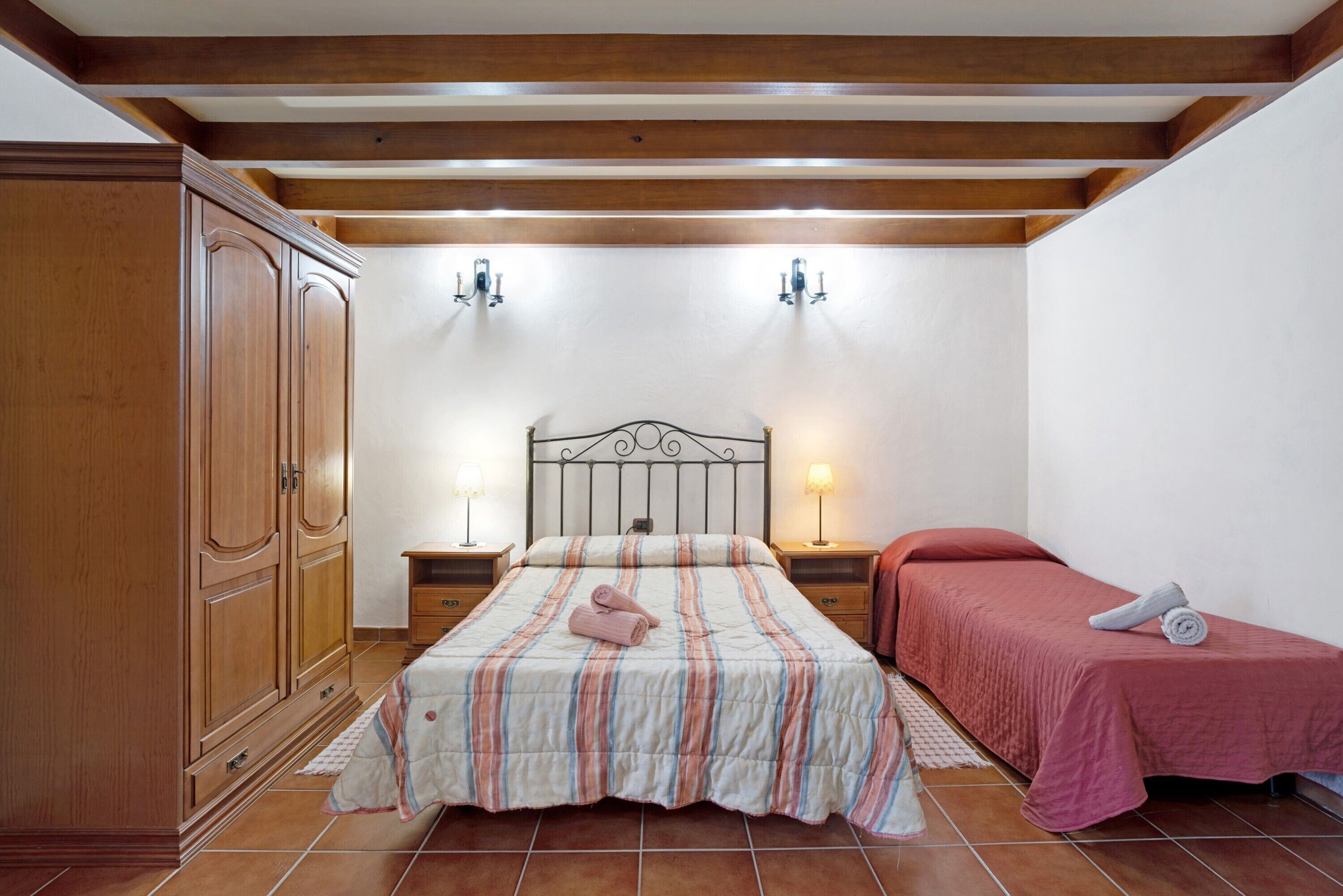 Una camera da letto con un letto, due comodini, un armadio e un tavolino di fianco al letto.