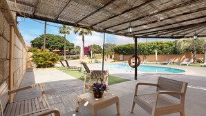 Une terrasse extérieure avec une piscine, des chaises longues et un espace abrité.