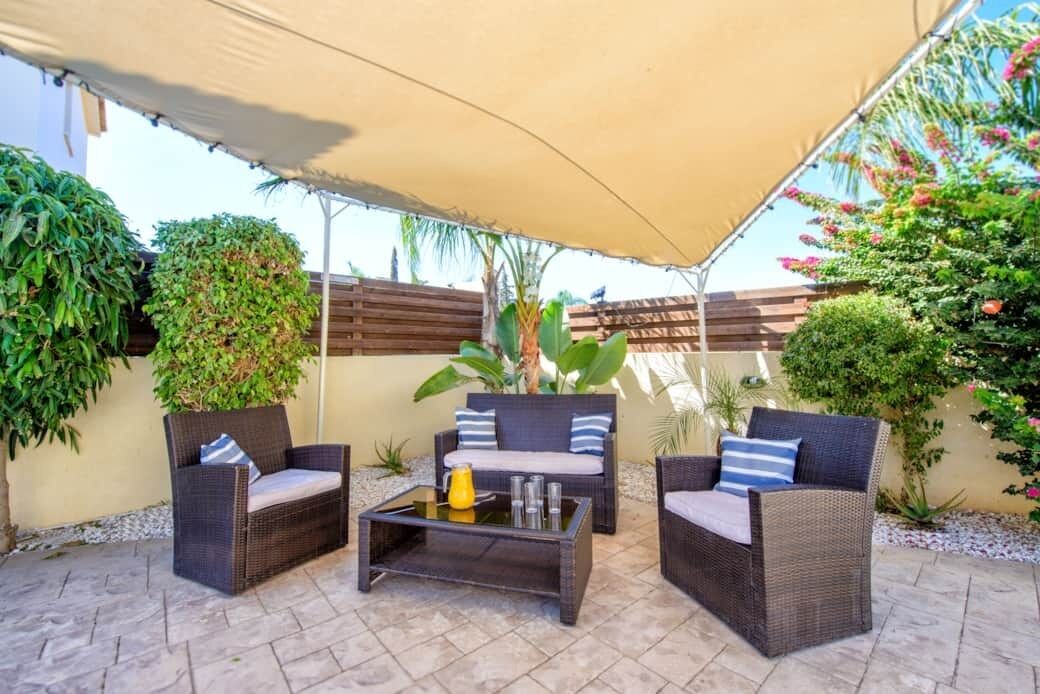 An outdoor patio area with wicker furniture, a table, and a canopy.