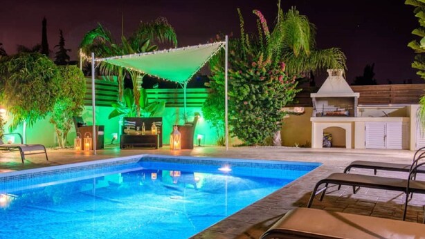 A swimming pool with lounge chairs, a barbecue area, and a covered seating area with ambient lighting. - Villa Sophia - 3 bed villa with private pool, 2 min walk to beach and internet (Paralimni)