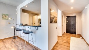 A modern kitchen with bar stools, a refrigerator, and a pendant light. - Chic Designer Apartment with Sea Views, Wi-Fi and Air Conditioning (Marbella)