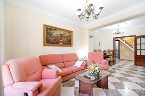 Un salon avec un canapé rose, une table basse et un tableau accroché au mur.