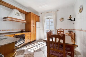 Une cuisine avec des meubles de rangement en bois, une cuisinière et une table à manger avec des chaises.