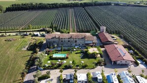 Un grand bâtiment doté d’une cour intérieure, entouré de champs, et devant lequel sont garés plusieurs camping-cars.