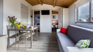 Un intérieur moderne comprenant un coin repas, un canapé et un téléviseur fixé au mur.