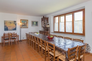 Ein Esszimmer mit einem langen Tisch, Stühlen, einer Stehlampe und Kunstwerken an den Wänden.