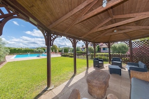 Ein überdachter Außenbereich mit Pool, Liegestühlen und Blick auf die umliegende Landschaft.