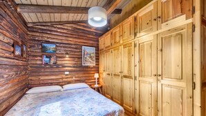 Une pièce aménagée comme un chalet en bois, avec un lit, des armoires en bois et des tableaux encadrés accrochés au mur.