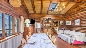 L’intérieur d’une cabane en rondins, avec une table à manger dressée, un canapé et un lustre.