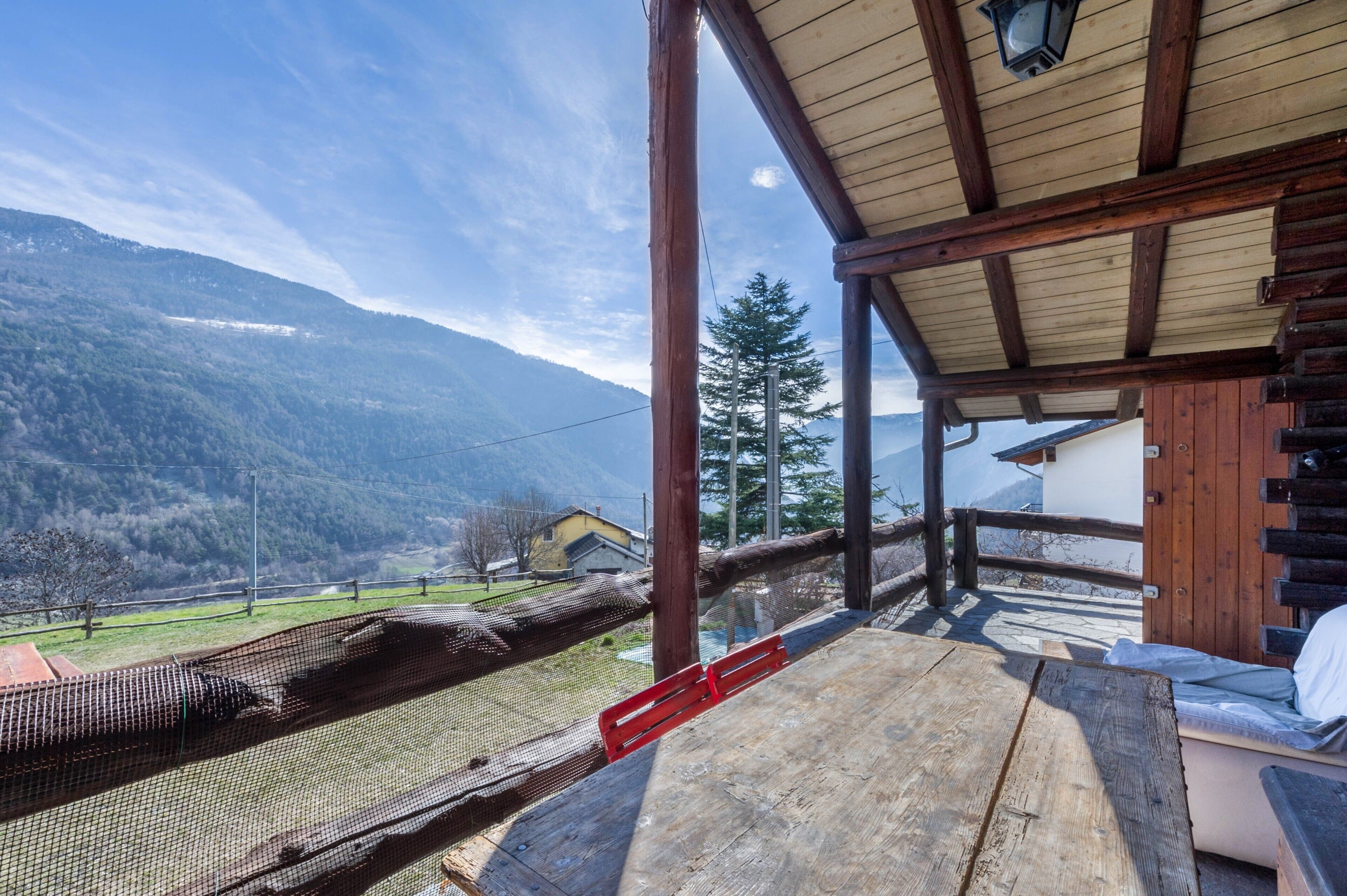 A wooden deck with a view of mountains and a house in the distance.