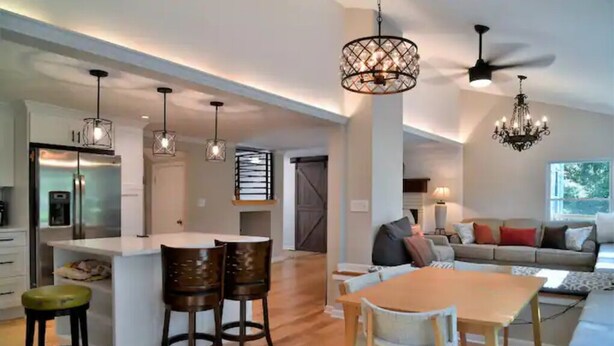 A spacious living area with a large sofa, a dining table with chairs, and a kitchen area with a refrigerator and bar stools.