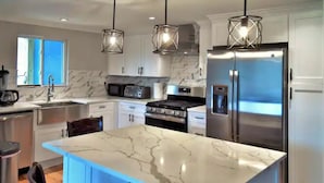 A modern kitchen with a central island, stainless steel appliances, and pendant lighting.