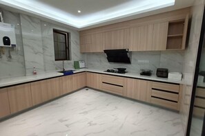 Een moderne keuken met marmeren aanrechtbladen, houten keukenkastjes en een ingebouwde magnetron.