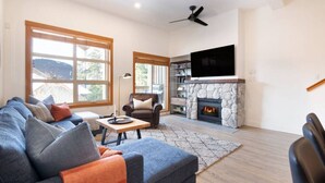 Una sala de estar con chimenea de piedra, un sofá, una silla y un televisor.