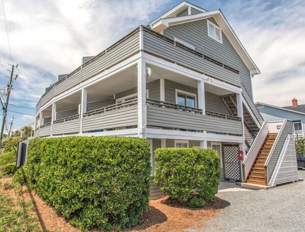A two-story house with a balcony on the upper floor, a covered porch, and a staircase leading to the upper level.