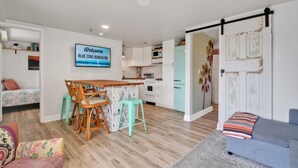 A modern kitchen with white cabinets, a teal refrigerator, and a wooden dining table with two chairs. - Blue Zone Bungalow! 150 yards to the beach & close to cafes! (Wrightsville Beach)