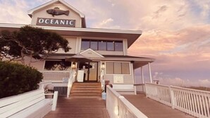 A coastal building named "OCEANIC" with a wooden deck and white railings. - Blue Zone Bungalow! 150 yards to the beach & close to cafes! (Wrightsville Beach)