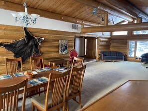 Ein rustikales Holzhaus-Interieur mit Essbereich, Kamin und einem großen Fellteppich.