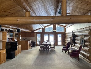 Ein rustikales Blockhaus-Interieur mit Essbereich, Küche und einem Bereich für Unterhaltung.