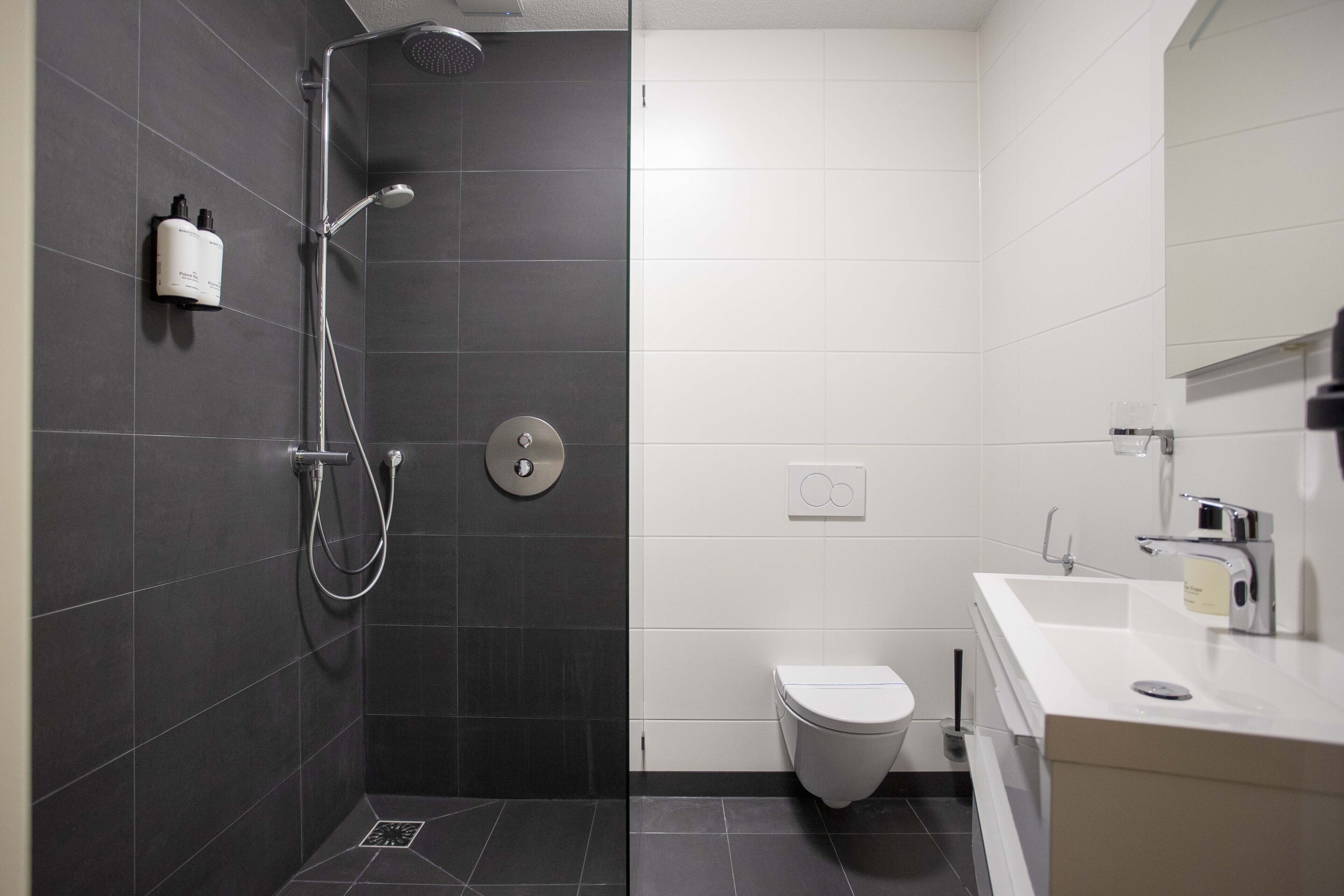 A modern bathroom with a shower, toilet, and sink.