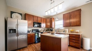 Une cuisine moderne avec des meubles en bois, des appareils en acier inoxydable et un îlot central.