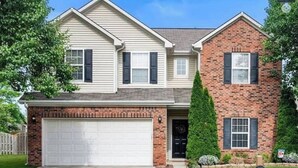 Une maison à deux étages avec un garage, une façade en briques et une pelouse bien entretenue.