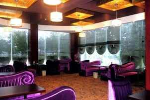 Un restaurante con asientos tapizados de color morado, ventanas grandes y una alfombra estampada.