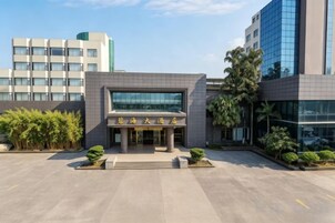 Un edificio moderno con fachada de vidrio, una escalera que lleva a la entrada y un estacionamiento al frente.