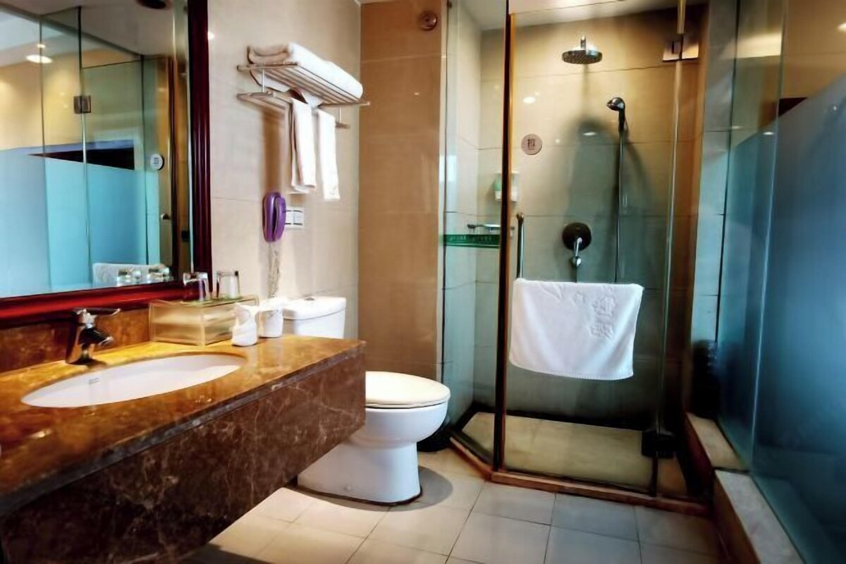 A modern bathroom with a marble sink, white toilet, and a glass-enclosed shower area.