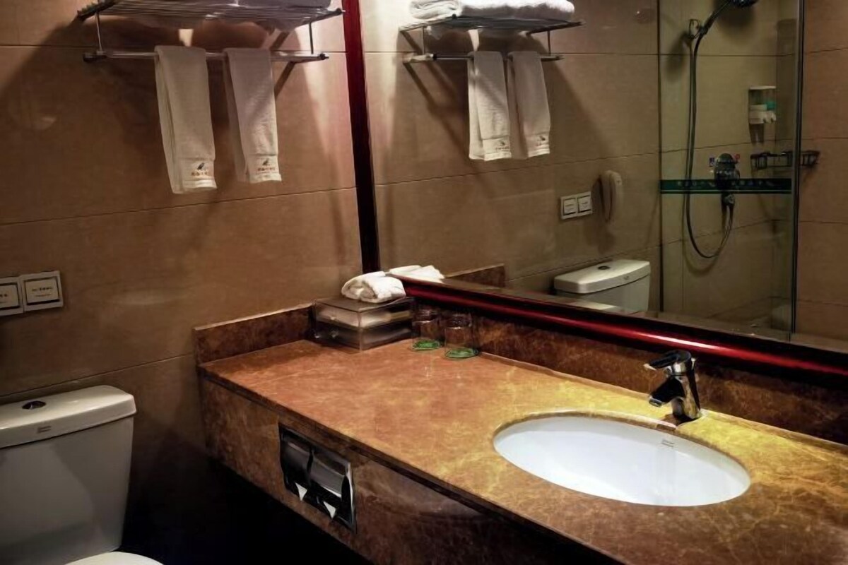 A bathroom with a marble sink, a mirror, a towel rack, and a glass shower enclosure.