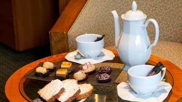 Une table avec une théière, deux tasses et une variété de pâtisseries et de sandwichs.