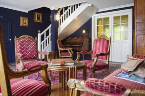 A room with a staircase, a piano, and red upholstered furniture. - Logis Hotel la Source Bleue (Gudmont)