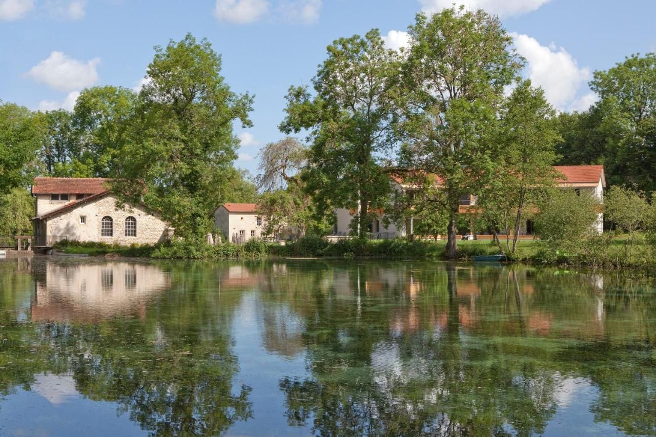 Um cenário tranquilo à beira do lago, com edifícios de pedra e vegetação exuberante.