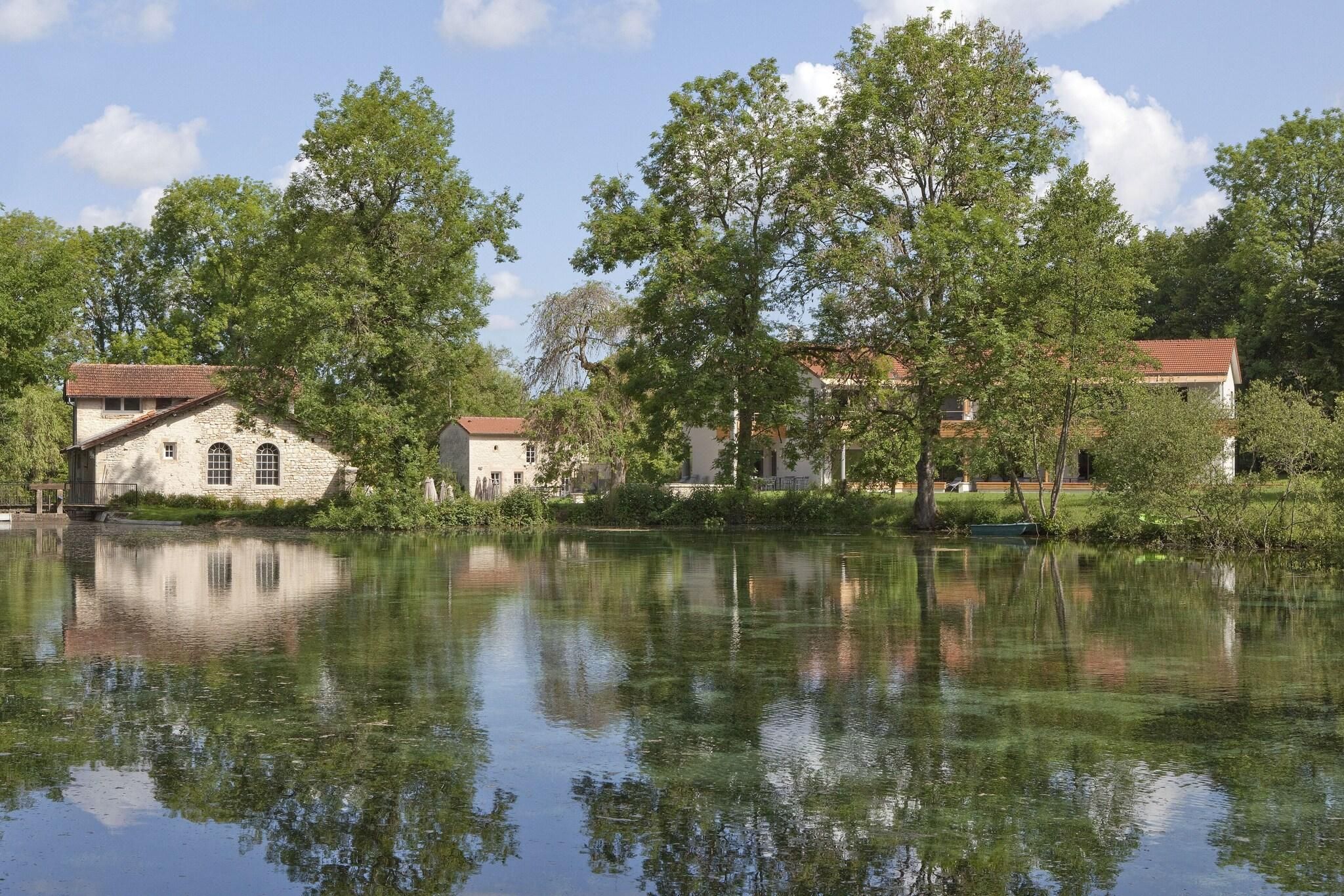 A serene lakeside scene with stone buildings and lush greenery.