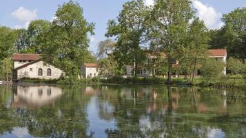 A serene lakeside scene with stone buildings and lush greenery.