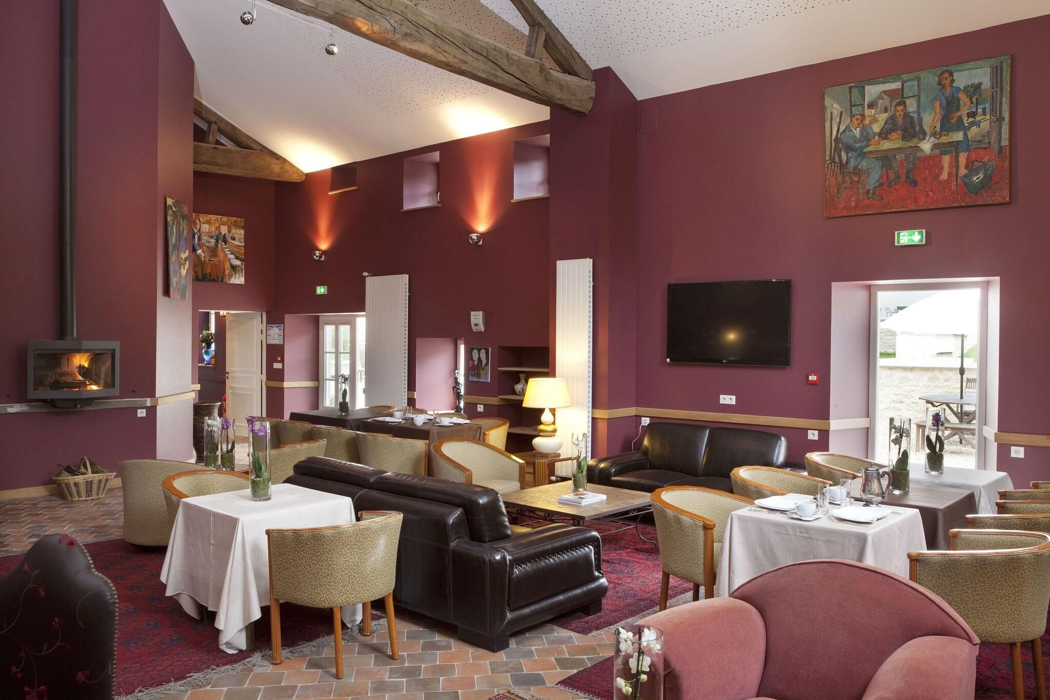A hotel lobby with a fireplace, seating areas, and a television.