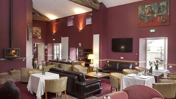 A hotel lobby with a fireplace, seating areas, and a television.