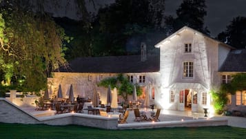 A stone building with a large patio area, outdoor seating, and a well-lit entrance.