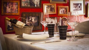 Una mesa de comedor con copas de vino, una cesta de botellas y tazas negras.