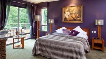 A bedroom with a large bed, a painting on the wall, and a balcony with a table and chairs.