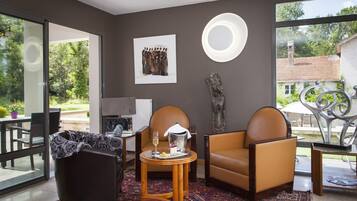 A modern living room with a large window, a fireplace, and a dining area with a table and chairs.