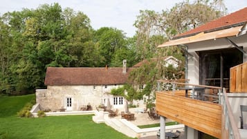 A stone house with a wooden deck and outdoor seating area.