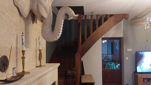 A room with a fireplace, a large decorative sculpture, a staircase, and a television. - Maison Pierre 9 Couchages Piscine Chauffée Jacuzzi (Abzac)