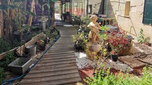 A wooden pathway leading to a covered area with potted plants and a statue. - Maison Pierre 9 Couchages Piscine Chauffée Jacuzzi (Abzac)