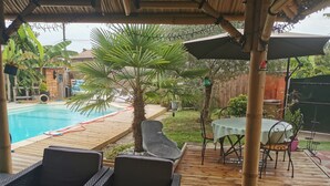 A covered outdoor area with a pool, lounge chairs, a table, and a dining table. - Maison Pierre 9 Couchages Piscine Chauffée Jacuzzi (Abzac)