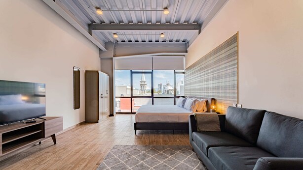 Ein modernes Schlafzimmer mit einem großen Bett, einem Fernseher und einer Couch.