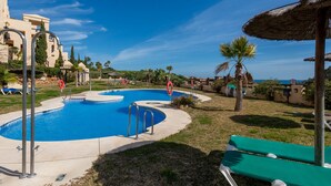 Ein Pool mit kreisförmigem Design, umgeben von Liegestühlen und einer Palme.