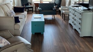 Una sala de estar con ventilador de techo, un sofá, una mesa de centro, un televisor y un aparador.