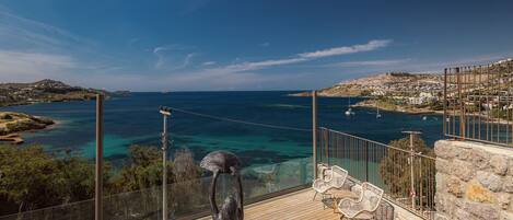 A terrace with a view of the sea, a statue, and outdoor furniture.